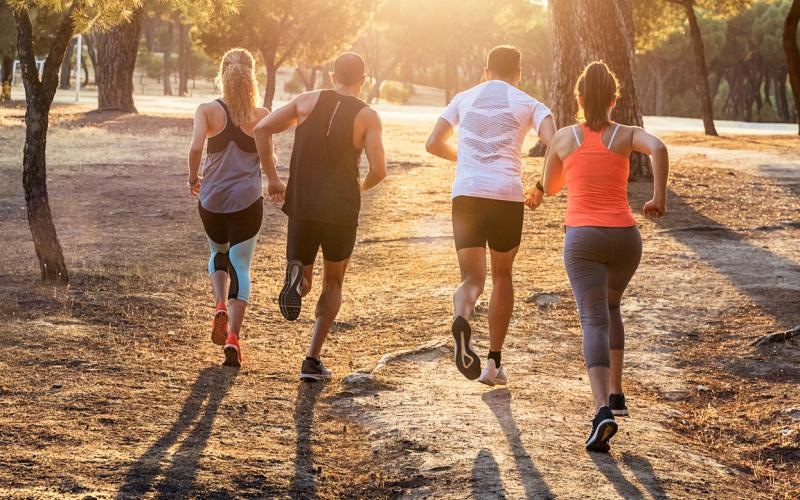 a group of people running on a path with trees on either side